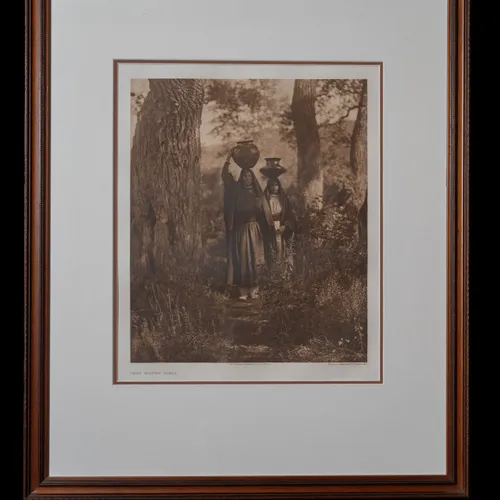 Taos Water Girls photogravure by Edward S. Curtis, 1905 - two Taos women in traditional dress carrying water jars on their heads between tall pine trees